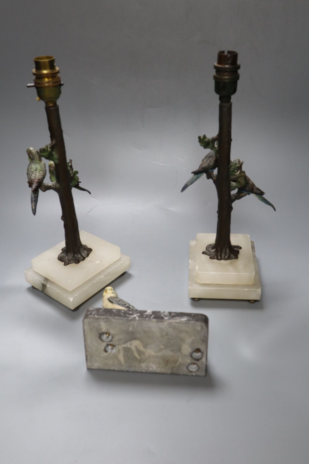A pair of cold painted metal budgerigar lamps, height 28cm excl. light fitting and a cold painted metal budgerigar table lighter, width